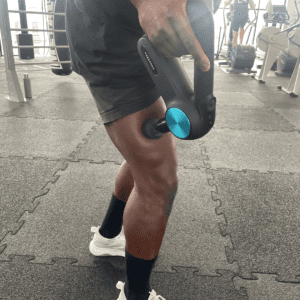 Utilisation d'un pistolet Theragun sur les jambes.