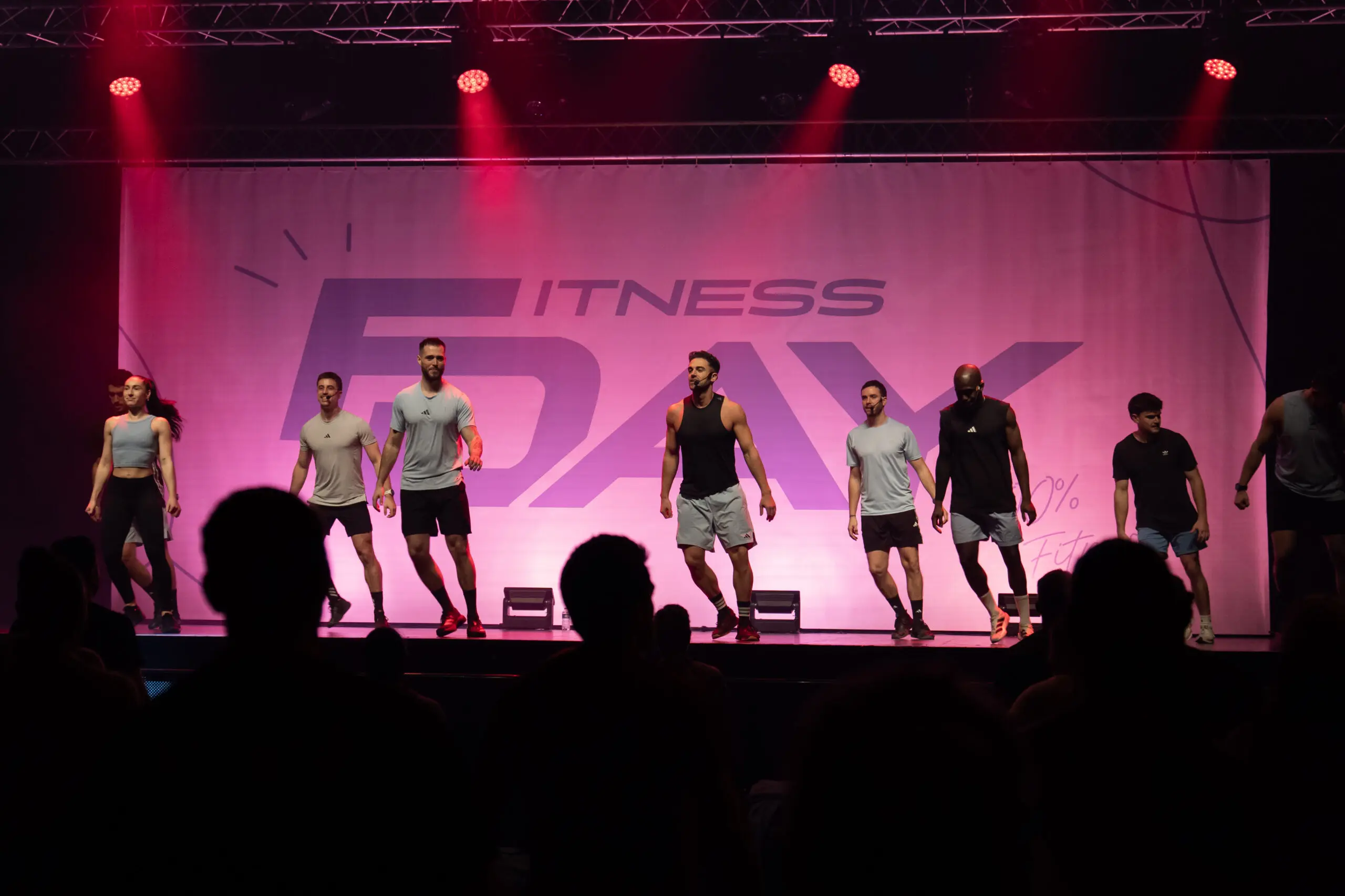 Équipe fitness en action sur scène ambiance rose au FitDay